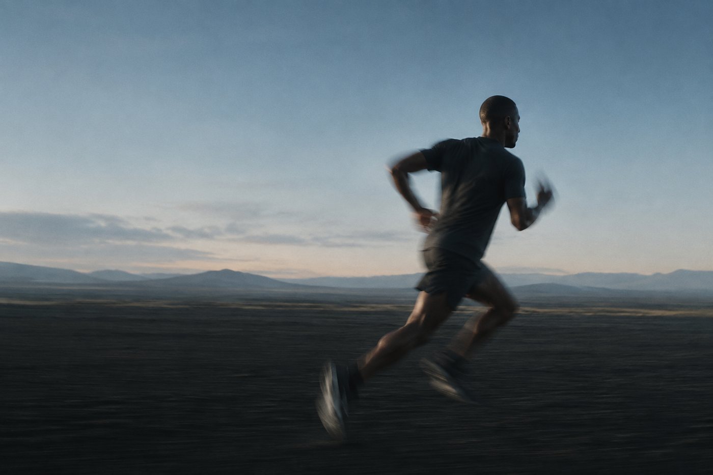 A runner at dawn holding pace across an open plain, the distance still ahead